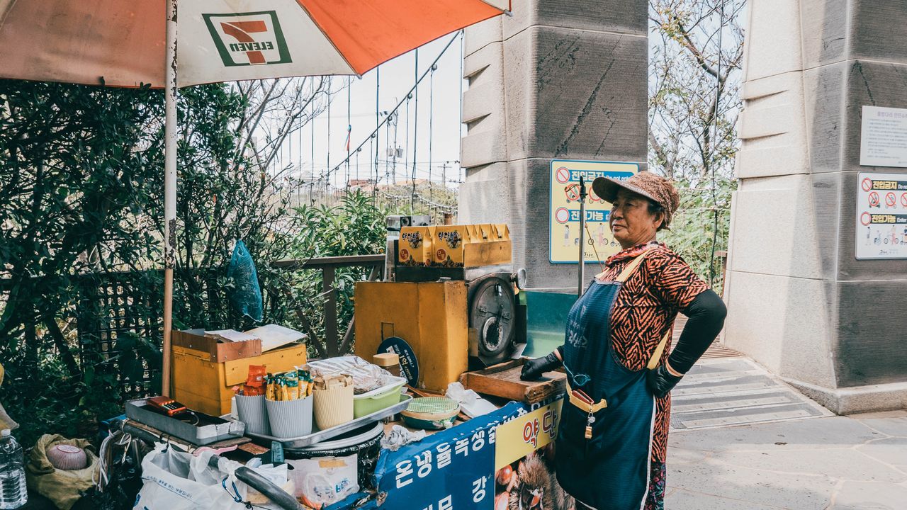 A female street vendor by her food cart in Jeju-si, South Korea on a sunny day.